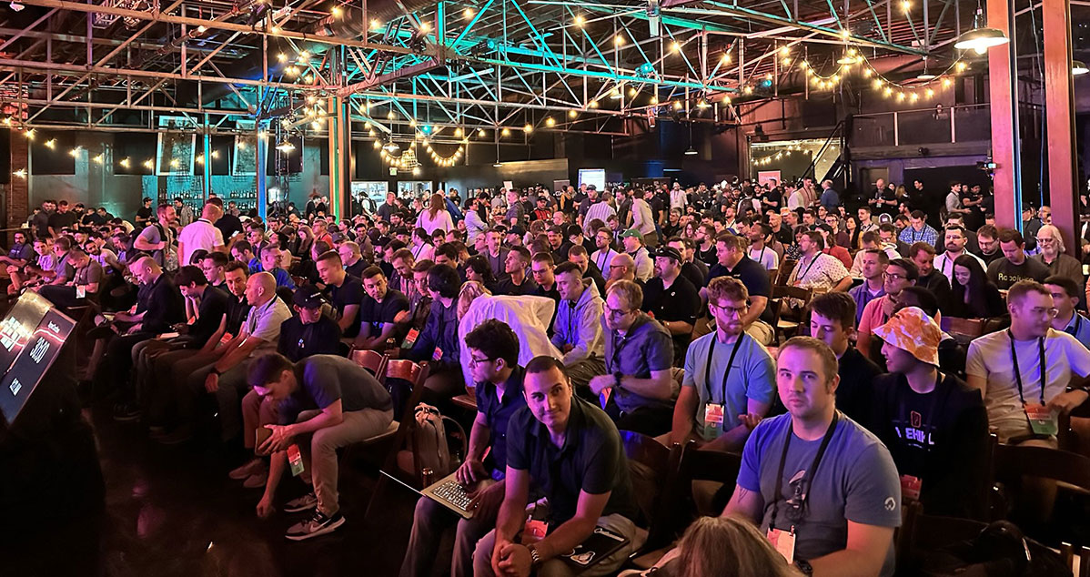 Large audience of developers seated at Laracon USA, under a venue lit with string lights and vibrant stage lighting, waiting for a keynote or presentation to begin.