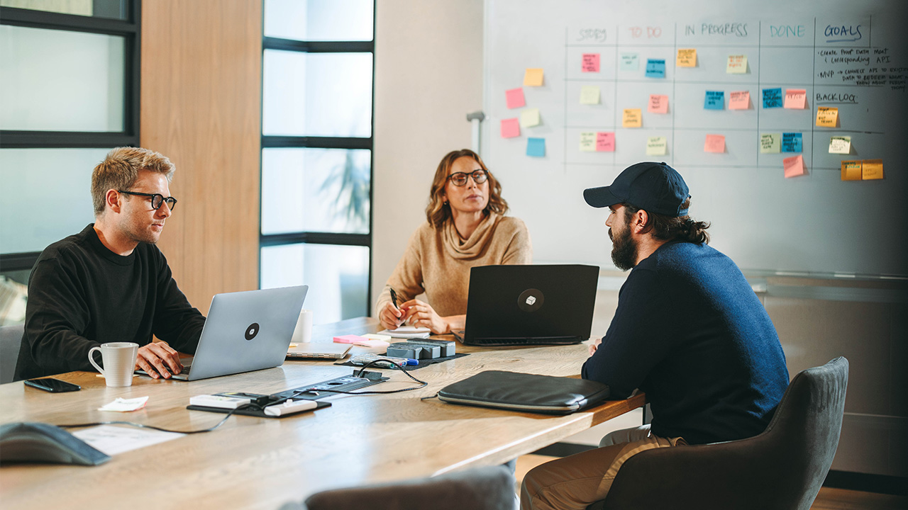 Outsourced software development team reviewing project tasks and roadmap in a meeting room.