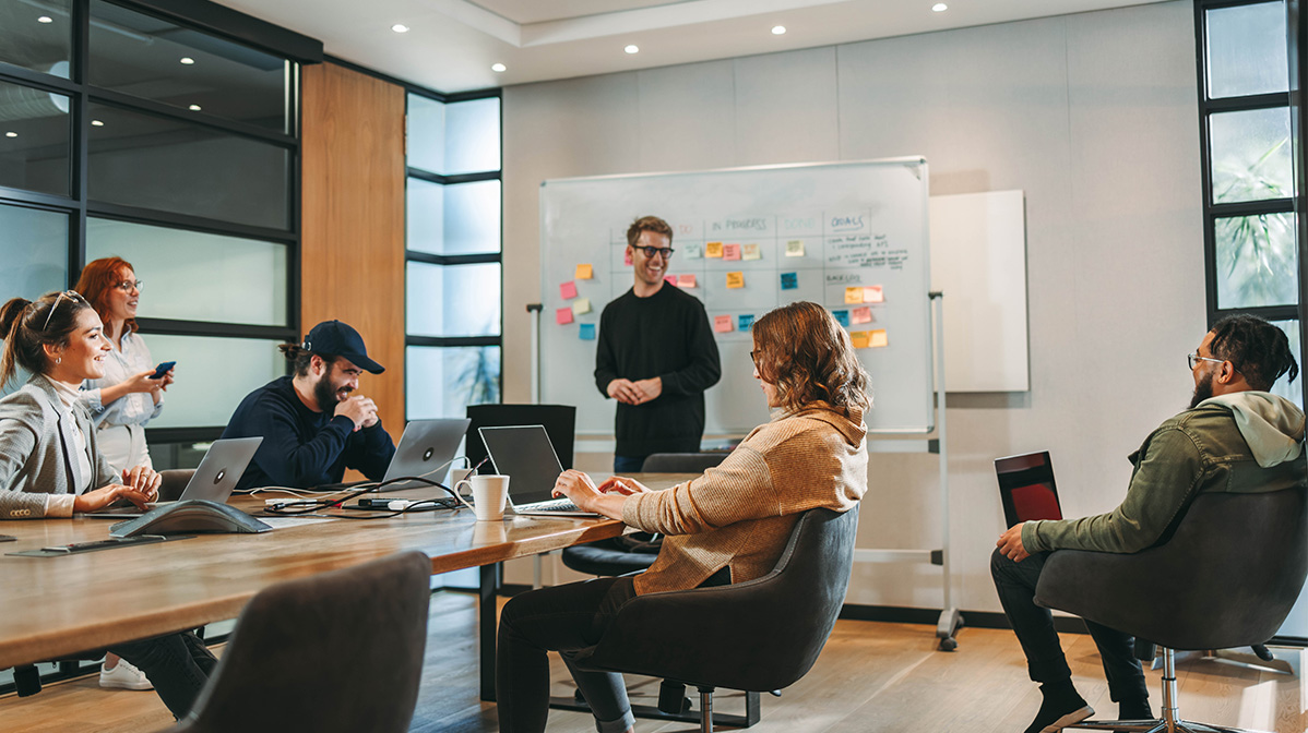 Team in a planning meeting in front of a Kanban board, illustrating the collaboration required for custom software development.